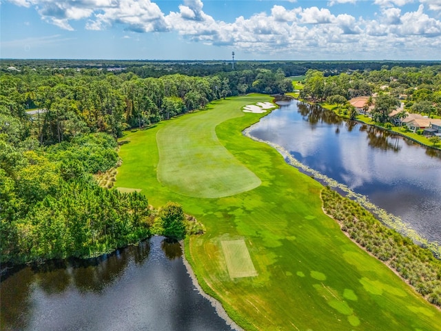 drone / aerial view with a water view, view of golf course, and a view of trees