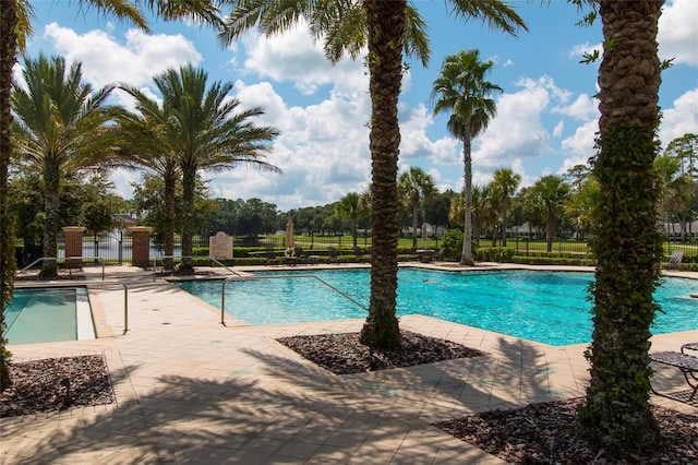 pool with a patio area and fence