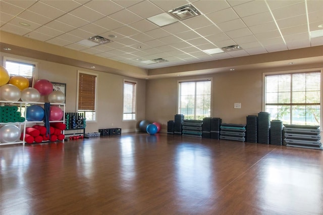 exercise area with a paneled ceiling, wood finished floors, and visible vents