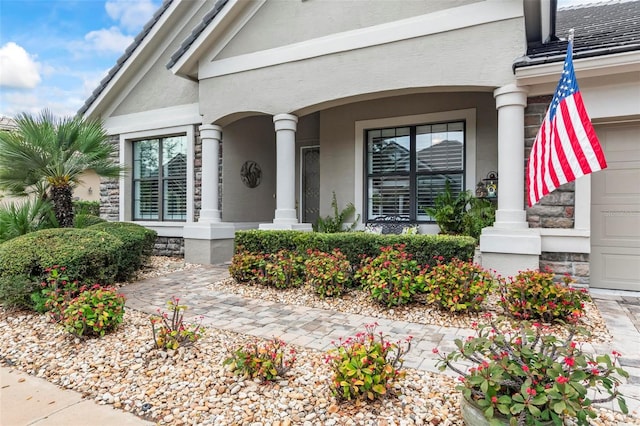 view of exterior entry featuring a porch, stucco siding, and an attached garage