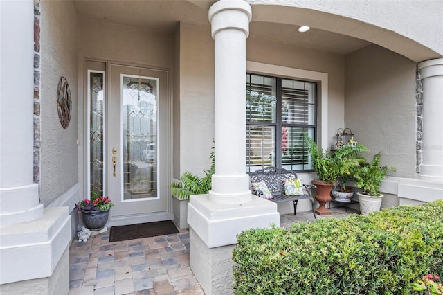 property entrance featuring a porch and stucco siding