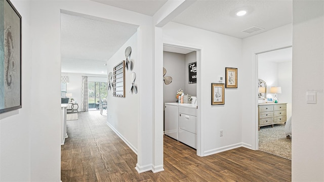 corridor featuring visible vents, washer and dryer, baseboards, and dark wood-style flooring