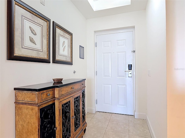 doorway to outside with light tile patterned floors, baseboards, and a skylight