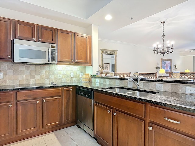 kitchen featuring a notable chandelier, a sink, backsplash, stainless steel appliances, and dark stone counters