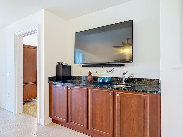 bar featuring light tile patterned floors, baseboards, and a sink