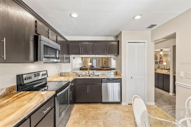 kitchen with dark brown cabinets, stainless steel appliances, light countertops, and a sink