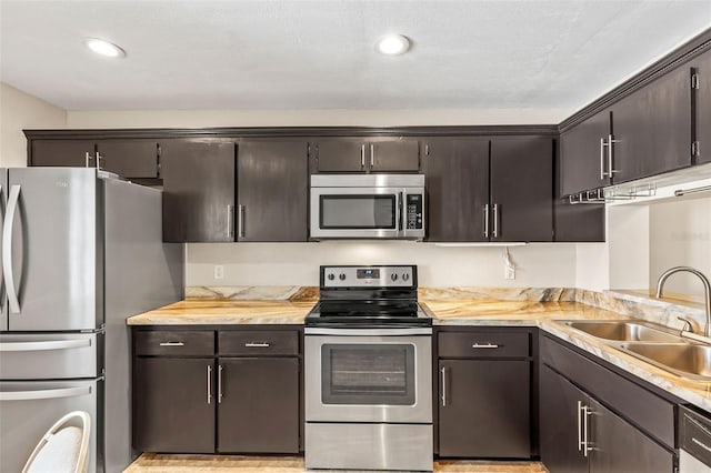 kitchen with a sink, dark brown cabinets, appliances with stainless steel finishes, and light countertops