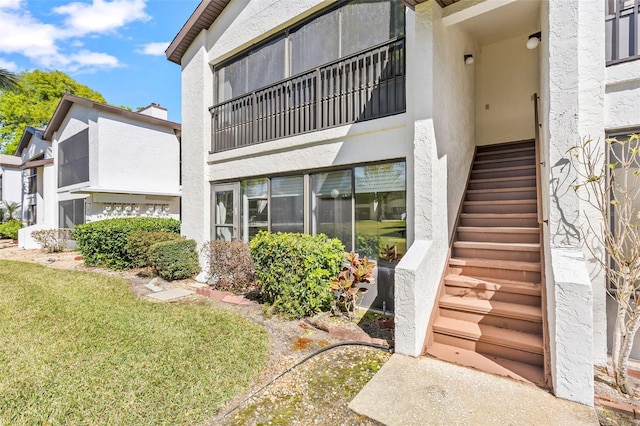 view of exterior entry featuring stucco siding and a yard