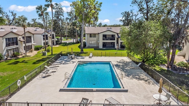 pool featuring a patio, a lawn, fence, and a residential view