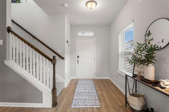 entrance foyer featuring stairway, wood finished floors, and baseboards