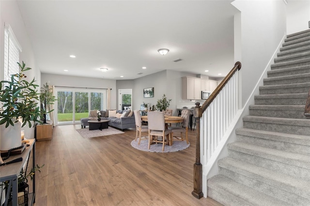 living area featuring stairs, light wood-style flooring, recessed lighting, and visible vents