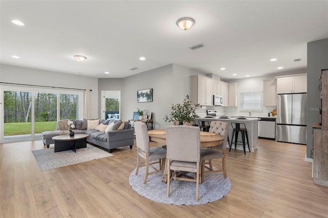 dining area featuring visible vents, light wood-style floors, and a healthy amount of sunlight