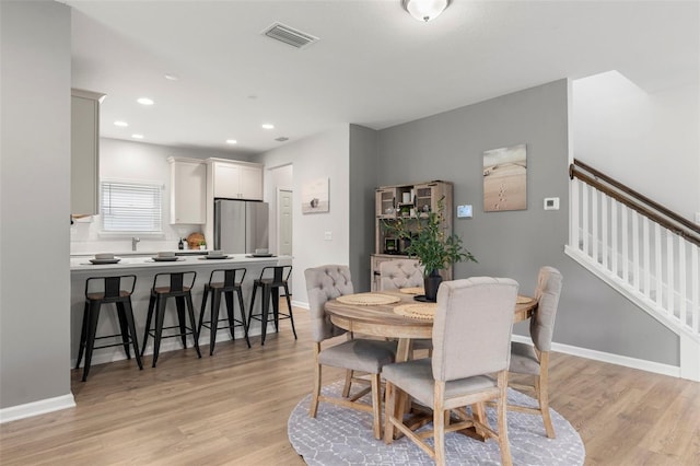 dining space with visible vents, recessed lighting, light wood finished floors, baseboards, and stairs