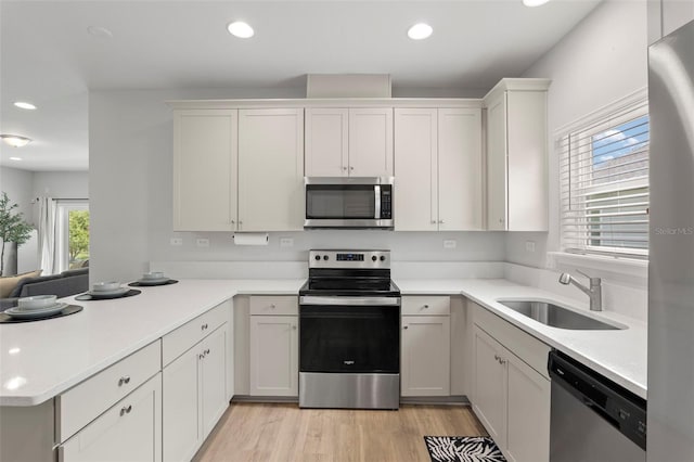 kitchen featuring a peninsula, stainless steel appliances, light countertops, and a sink