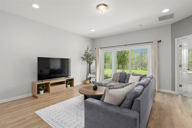 living room featuring a wealth of natural light, visible vents, and wood finished floors