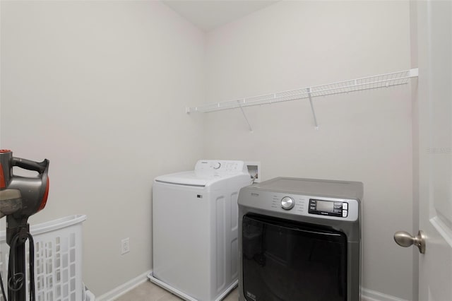 clothes washing area featuring washer and clothes dryer, laundry area, and baseboards