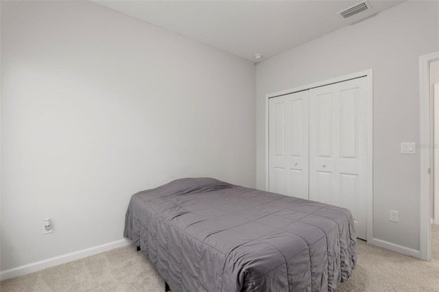 carpeted bedroom featuring visible vents, baseboards, and a closet