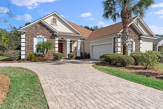 view of front facade with a garage, decorative driveway, stone siding, and stucco siding