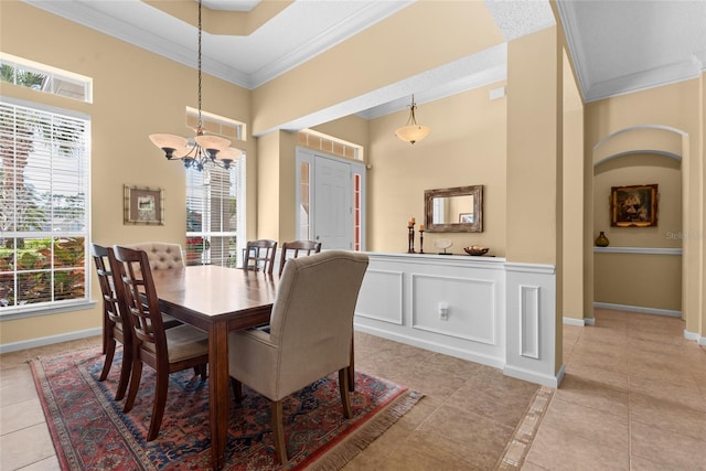 dining space with light tile patterned floors, a decorative wall, and ornamental molding