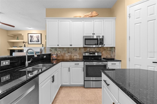 kitchen featuring a sink, stainless steel appliances, white cabinets, light tile patterned floors, and decorative backsplash