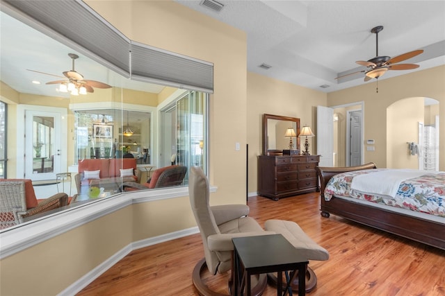 bedroom featuring light wood finished floors, visible vents, multiple windows, and arched walkways