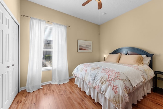 bedroom with a closet, ceiling fan, baseboards, and wood finished floors