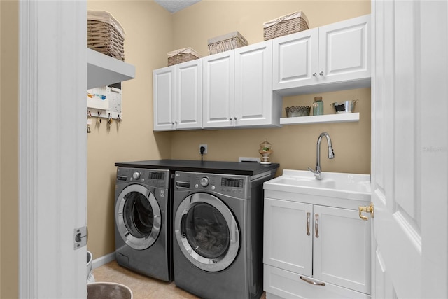 laundry room with cabinet space, washing machine and dryer, baseboards, and a sink