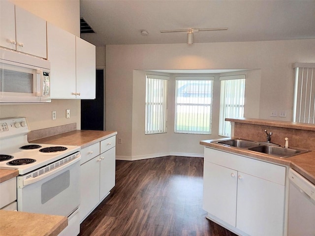 kitchen featuring a sink, white cabinetry, white appliances, baseboards, and dark wood-style flooring