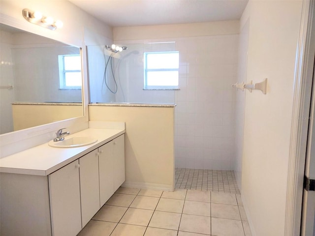 full bath featuring tile patterned flooring, walk in shower, vanity, and a healthy amount of sunlight