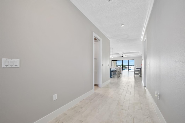 hall featuring a textured ceiling, light wood-style floors, and baseboards