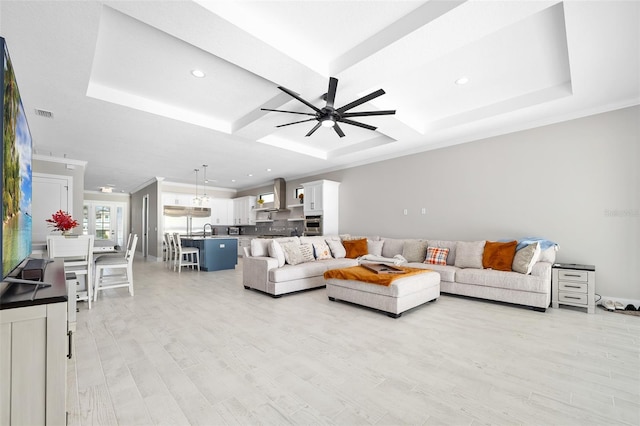 living room with visible vents, light wood-style floors, a ceiling fan, and crown molding