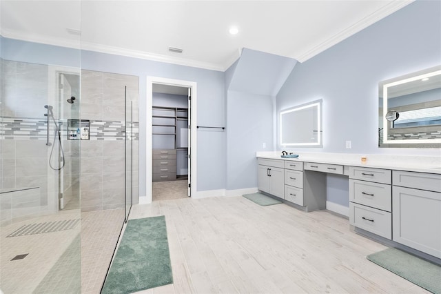 full bath with visible vents, ornamental molding, wood finished floors, double vanity, and tiled shower