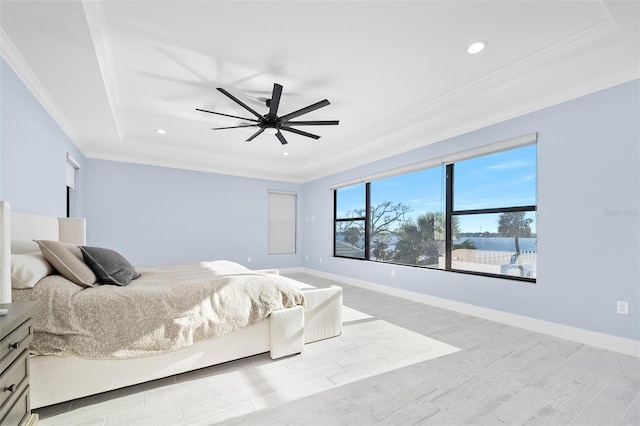 bedroom featuring a tray ceiling, wood finished floors, baseboards, and ornamental molding