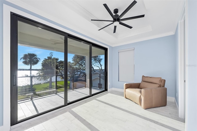 living area with crown molding, ceiling fan, baseboards, a tray ceiling, and wood finished floors