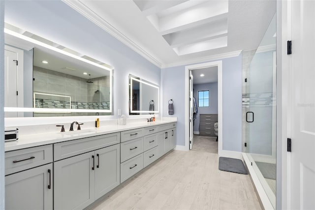 full bathroom featuring double vanity, a shower stall, crown molding, and a sink