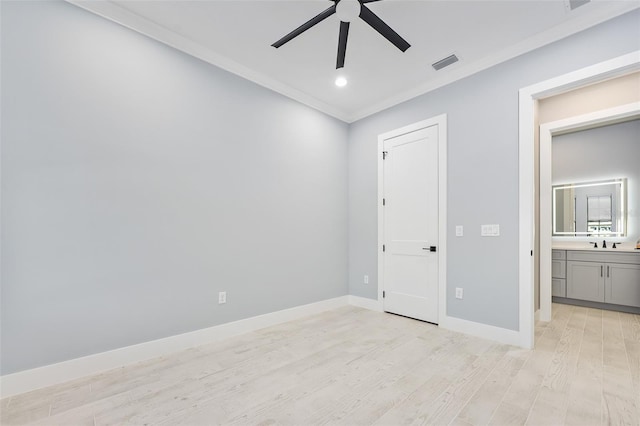 unfurnished bedroom featuring visible vents, crown molding, baseboards, light wood-style floors, and a sink