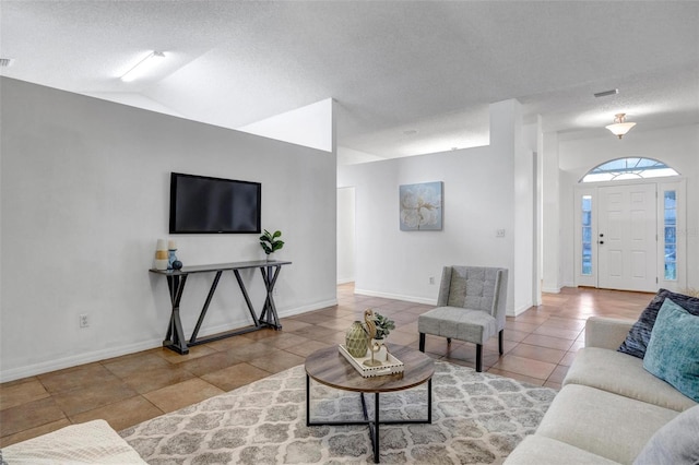 tiled living room with a textured ceiling, baseboards, and vaulted ceiling