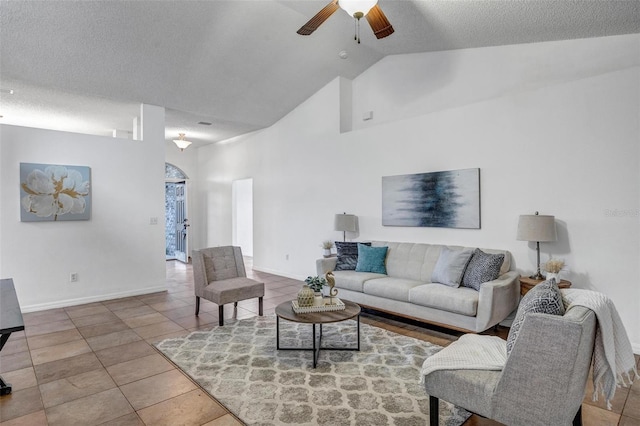 tiled living area with ceiling fan, high vaulted ceiling, baseboards, and a textured ceiling
