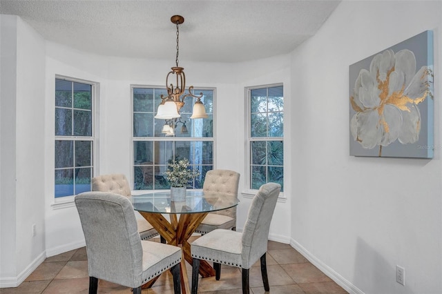 tiled dining space with a notable chandelier, a textured ceiling, and baseboards