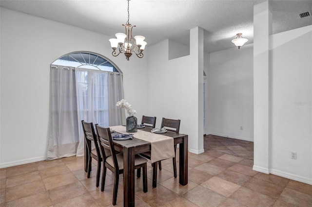 dining space featuring a notable chandelier, baseboards, a textured ceiling, and visible vents