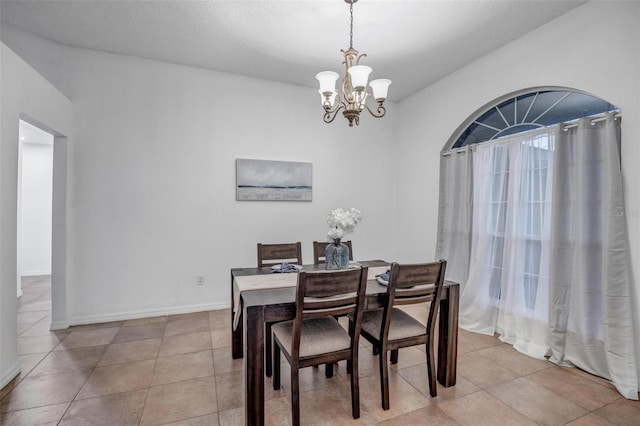dining room featuring light tile patterned floors, baseboards, a textured ceiling, and an inviting chandelier
