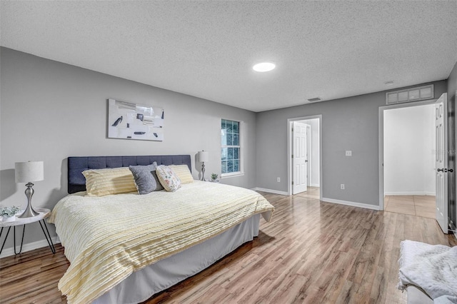 bedroom with baseboards, visible vents, and light wood finished floors
