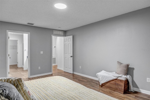 bedroom with a textured ceiling, light wood-style floors, and baseboards