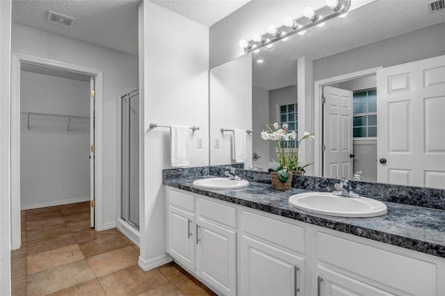 bathroom with a sink, visible vents, a stall shower, and a spacious closet