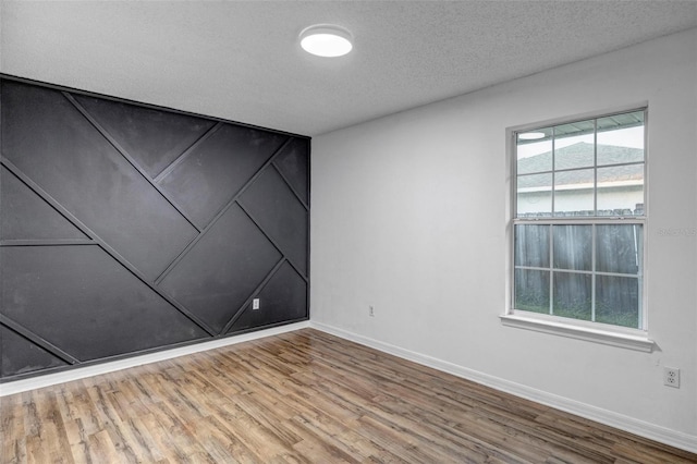 unfurnished room featuring baseboards, a textured ceiling, and wood finished floors