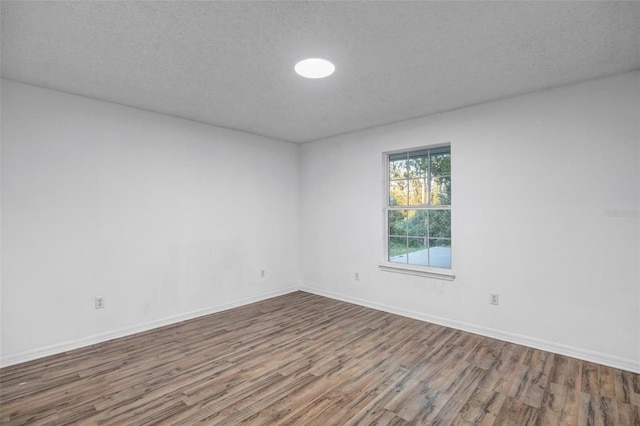 spare room featuring baseboards, a textured ceiling, and wood finished floors