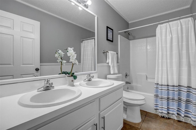 full bathroom with double vanity, a textured ceiling, toilet, and a sink