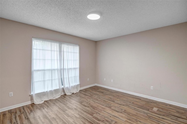 spare room with wood finished floors, baseboards, and a textured ceiling