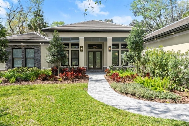 exterior space featuring a tiled roof, stucco siding, french doors, and a front yard