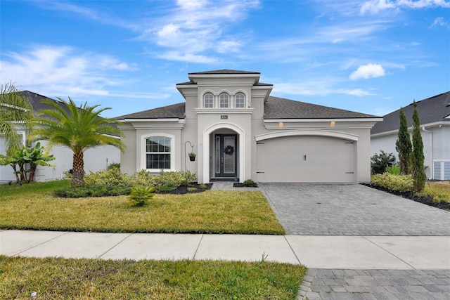 mediterranean / spanish-style home with stucco siding, a front yard, decorative driveway, and a garage